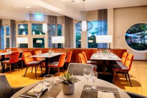 a restaurant with tables and chairs and windows at Welcome Hotel Marburg in Marburg an der Lahn