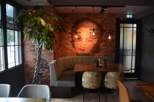 een eetkamer met een bakstenen muur met een gezicht geschilderd op de muur bij Hotel Restaurant de Engel in Lisse