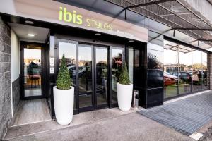 Deux grands pots blancs avec des arbres à l'extérieur d'un magasin dans l'établissement ibis Styles Roma Vintage, à Rome