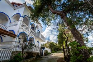 a building with blue and white trim and a tree at Velendzas Holidays in Alikanas