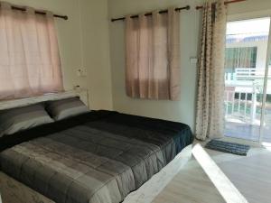 a bedroom with a bed and a large window at บ้านสวนคุณตา Baan Suan Khun ta in Ko Chang