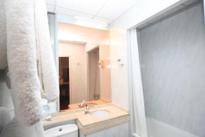 a bathroom with a sink, mirror, towel rack and towel dispenser at Bristol Hotel in Gibraltar