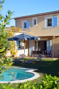 a pool with an umbrella and chairs and a house at Lagrange Vacances - Le Clos Savornin in Saint-Saturnin-lès-Apt