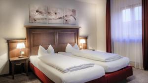 2 łóżka w pokoju hotelowym z białymi poduszkami w obiekcie Restaurant-Café-Pension Himmel w mieście Landshut