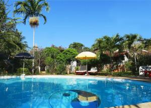 a large swimming pool with two umbrellas in a yard at Frangipani Cottages in Diani Beach