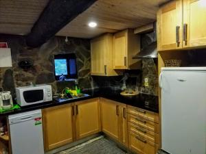 a kitchen with wooden cabinets and a white refrigerator at Refúgio do Fujaco in São Pedro do Sul