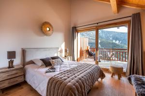 a bedroom with a bed and a balcony with a view at TERRESENS - Le Saphir in Vaujany