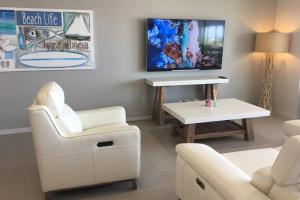 sala de estar con muebles blancos y TV de pantalla plana en Upmarket Comfortable Large 2 Bed 2 Bath, OCEAN VIEWS, 250m to BUDDINA BEACH! en Buddina
