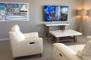 un soggiorno con mobili bianchi e TV a schermo piatto di BEACH Luxury Upmarket 2B 2B OCEAN VIEWS 250m to BUDDINA BEACH! a Buddina