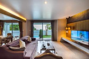 a living room with a couch and a large tv at Venice Beach Village Hua Hin Pool Villa in Cha Am