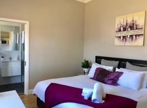 um quarto com uma grande cama branca com almofadas roxas em Renovated Little Cottage Aberdare Hunter Valley em Aberdare