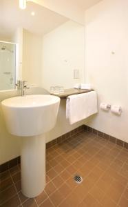 Baño blanco con lavabo y espejo en ibis Melbourne - Glen Waverley en Glen Waverley