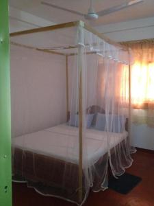 a bedroom with a canopy bed with white curtains at Paradise Beach House in Talalla South