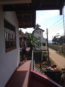 a woman standing on the balcony of a house at Paradise Beach House in Talalla South