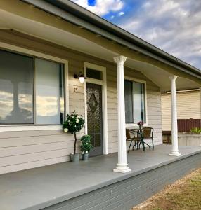 um alpendre de uma casa com duas colunas em Renovated Little Cottage Aberdare Hunter Valley em Aberdare