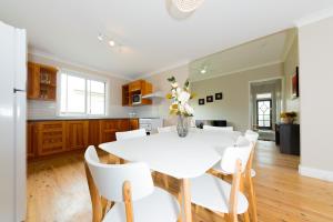 cocina y comedor con mesa blanca y sillas en Renovated Little Cottage Aberdare Hunter Valley, en Aberdare