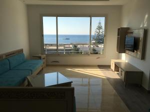 a living room with a blue couch and a large window at Arabesque Style - 2 appartements in Kelibia