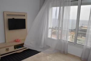 a room with a window with white curtains and a tv at Arabesque Style - 2 appartements in Kelibia