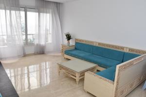 a living room with a blue couch and a table at Arabesque Style - 2 appartements in Kelibia