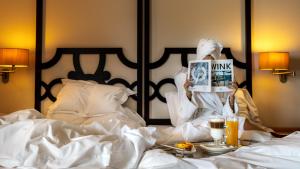 a woman is sitting on a bed reading a magazine at Pousada Convento de Tavira in Tavira