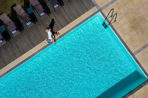 a woman standing next to a blue swimming pool at Pousada Convento de Tavira in Tavira