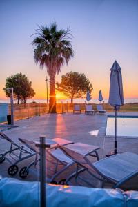 une piscine avec des tables, des parasols et un palmier dans l'établissement Casa e Natura, à Moriani-Plage
