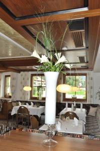 eine große weiße Vase mit Blumen auf einem Tisch in einem Restaurant in der Unterkunft Gasthof Schopper in Breitenbach am Inn