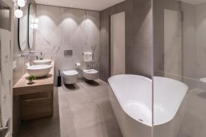 a bathroom with two sinks and a tub and two toilets at Sicilia's Art Hotel & Spa in Acitrezza