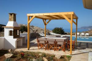 een tafel en stoelen onder een paviljoen naast een zwembad bij Lagada Resort in Makry Gialos