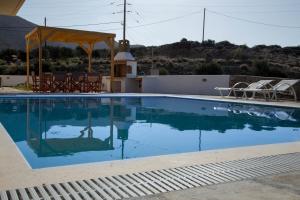 a swimming pool with chairs and a gazebo at Lagada Resort in Makry Gialos