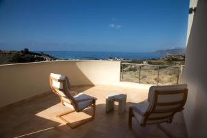 een balkon met 2 stoelen en een tafel en de oceaan bij Lagada Resort in Makry Gialos