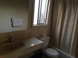 een badkamer met een wastafel, een toilet en een raam bij Discovery Inn in Vallejo