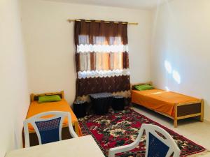 a small room with two beds and a window at Auberge Alferdaous in Tataouine