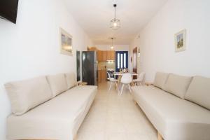 a living room with two white couches and a kitchen at Nefeli Apartments in Ayia Evfimia