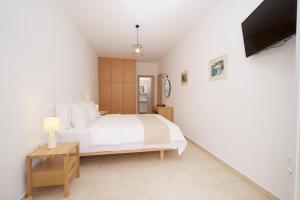 a bedroom with a white bed and a tv at Nefeli Apartments in Ayia Evfimia