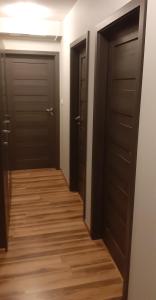korytarz z dwoma czarnymi drzwiami i drewnianą podłogą w obiekcie Hostel Tip Top w Gdańsku