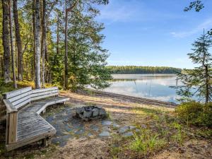 a wooden bench sitting next to a body of water at Holiday Home Villa populus by Interhome in Pertunmaa