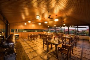 ein Restaurant mit Holztischen, Stühlen und Fenstern in der Unterkunft Woodstock Resorts in Madikeri