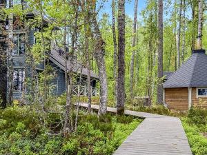 uma passagem de madeira que leva a uma casa na floresta em Holiday Home Villa populus by Interhome em Pertunmaa