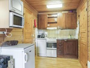 a kitchen with white appliances and wooden cabinets at Holiday Home Lomamaja 3 by Interhome in Raattama