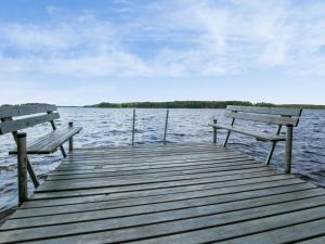 two benches sitting on a dock on a body of water at Holiday Home Villa ina by Interhome in Evijärvi