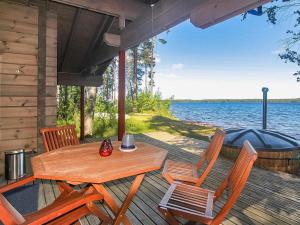 une terrasse en bois avec une table, des chaises et un bateau dans l'établissement Holiday Home Villa salix by Interhome, à Mäntyharju