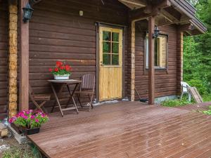 un porche de madera de una cabaña con mesa y flores en Holiday Home Hirsiniemi by Interhome en Vuoriniemi