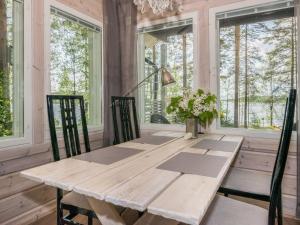 a wooden table and chairs in a room with windows at Holiday Home Villa ina by Interhome in Evijärvi