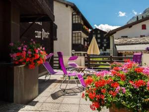 a group of purple chairs sitting on a patio with flowers at Apartment Zur Post by Interhome in Saas-Almagell