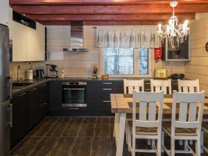 une cuisine avec des armoires noires et une table et des chaises en bois dans l'établissement Holiday Home Rölli 2 by Interhome, à Äkäslompolo
