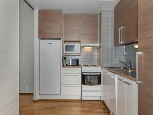 a kitchen with white appliances and wooden cabinets at Holiday Home Ylläs chalets 2301 by Interhome in Ylläsjärvi
