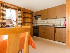 una cucina con armadi in legno, tavolo e finestra di Apartment Zur Post by Interhome a Saas-Almagell