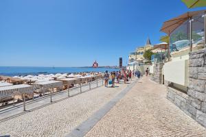 a beach with umbrellas and people walking down a sidewalk at Estoril BeachFront Balcony apartment in Estoril