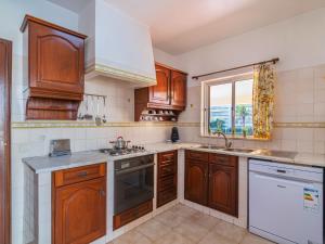 a kitchen with wooden cabinets and a sink and a window at Villa Flor de Maio by Interhome in Patroves